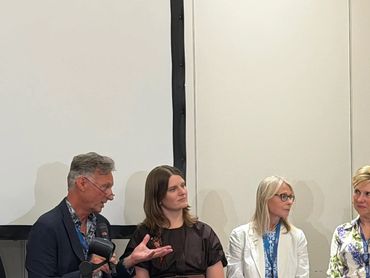 Four people seated, engaged in a discussion or panel event.