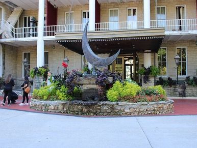 Crescent moon sculpture in front of a historic building entrance.