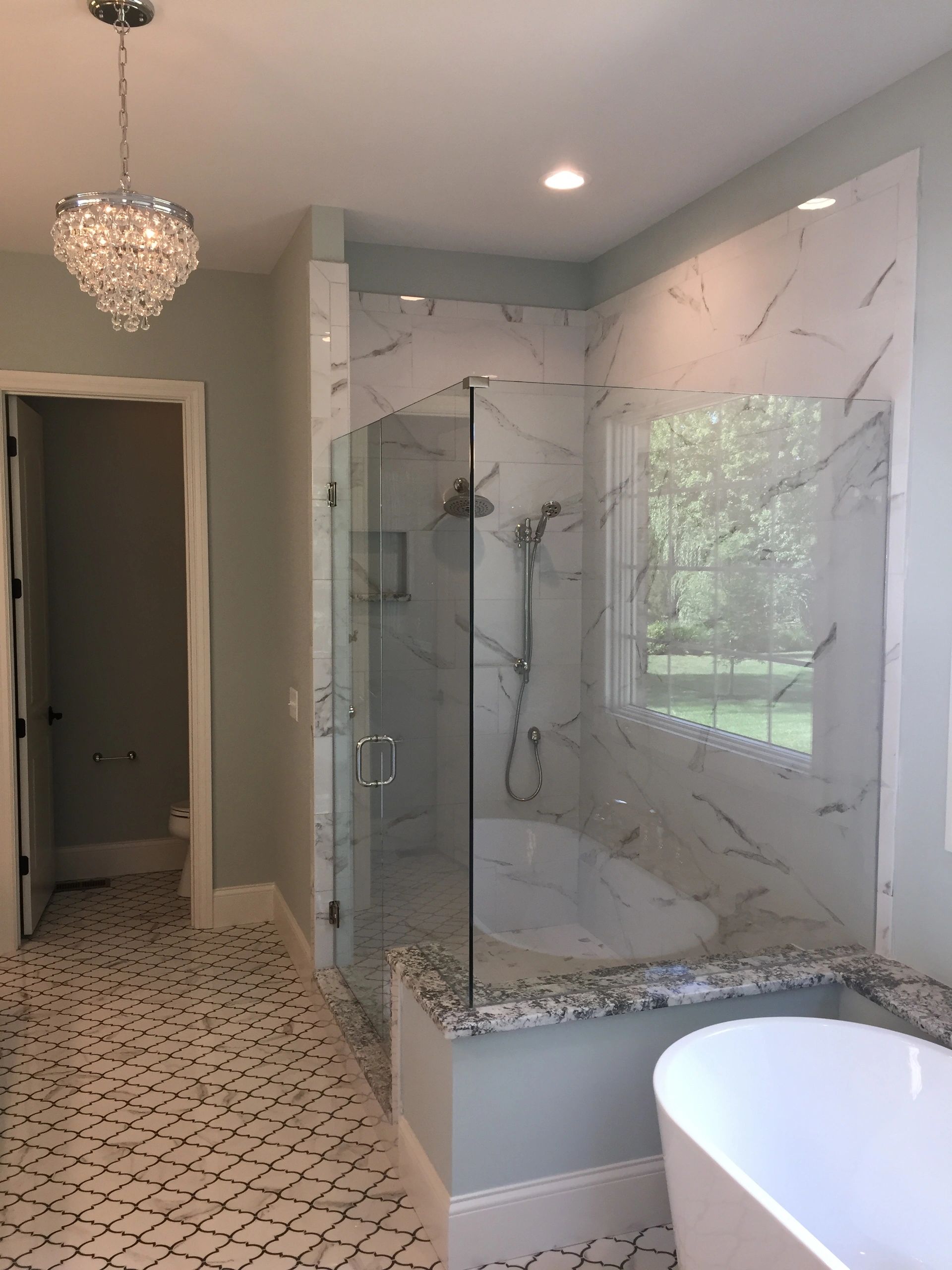 Modern bathroom with glass shower and chandelier.