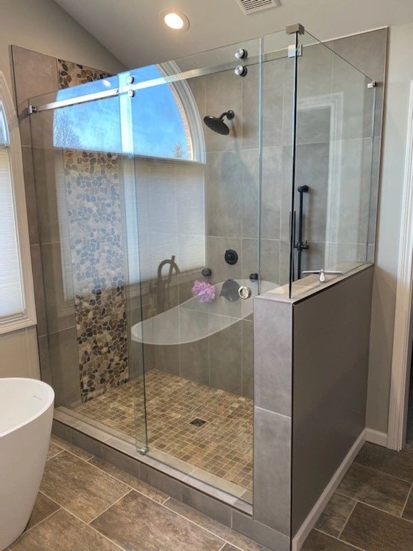 Modern glass shower enclosure with tiled interior and window.