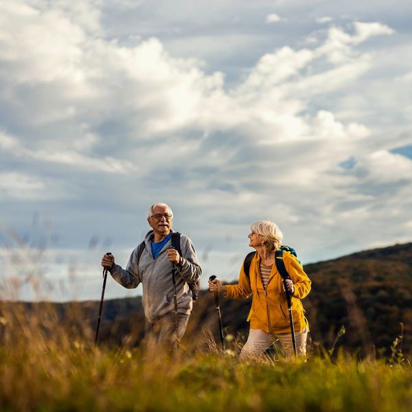 Senior couple hiking in nature with walking sticks.