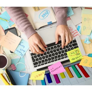 Laptop, with a messy desk and colorful sticky notes.