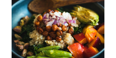Colorful bowl with quinoa, chickpeas, avocado, tomatoes, and greens.