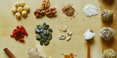 An assortment of nuts, seeds, spices, and energy balls on a wooden surface.