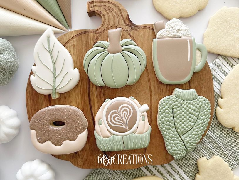 Autumn-themed decorated cookies with cozy and warm designs on wooden board.