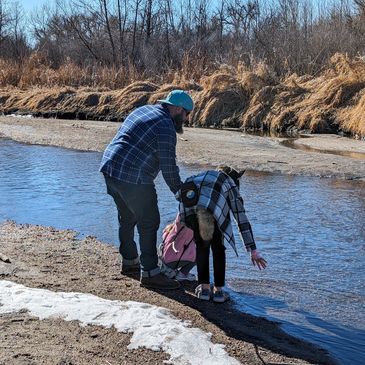 Image of Dave and two children along a river with dry grass in the background