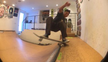 A skateboarder performing a trick on an indoor mini ramp.