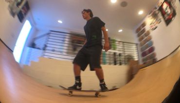 A person skateboarding indoors on a wooden ramp.