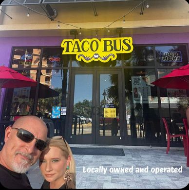 Taco Bus restaurant entrance with a couple posing in front.