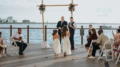 Couple exchanging vows at a waterfront wedding ceremony with guests seated.