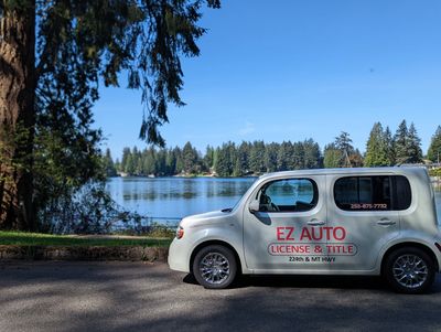 A white EZ Auto car parked near a lake with trees in the background.