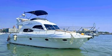 A sleek white yacht floating on calm water under a clear blue sky.