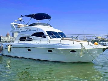 A sleek white yacht floating on calm water under a clear blue sky.
