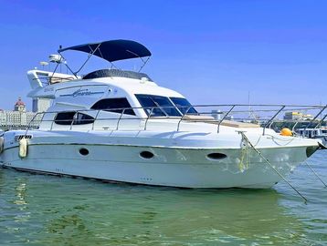 A sleek white yacht floating on calm water under a clear blue sky.