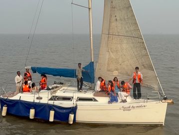 Group wearing orange life jackets on a sailboat with a blue canopy on calm water.