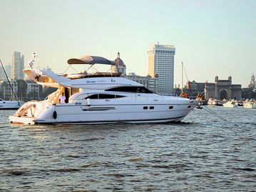 A white yacht sailing near a city waterfront at sunset.