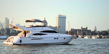 A white yacht sailing near a city waterfront at sunset.