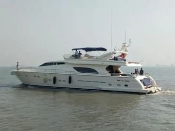 Luxury white yacht cruising on calm water under overcast sky.