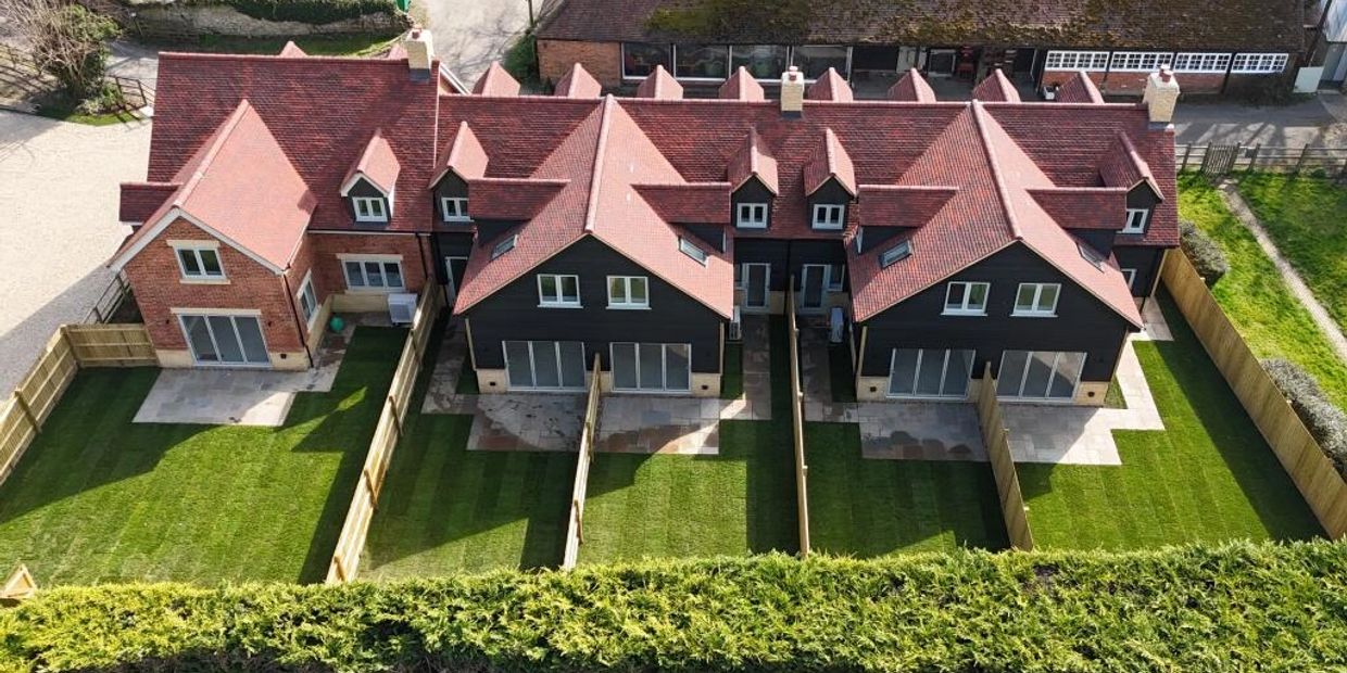 Aerial view of newly built modern houses with fenced lawns.
