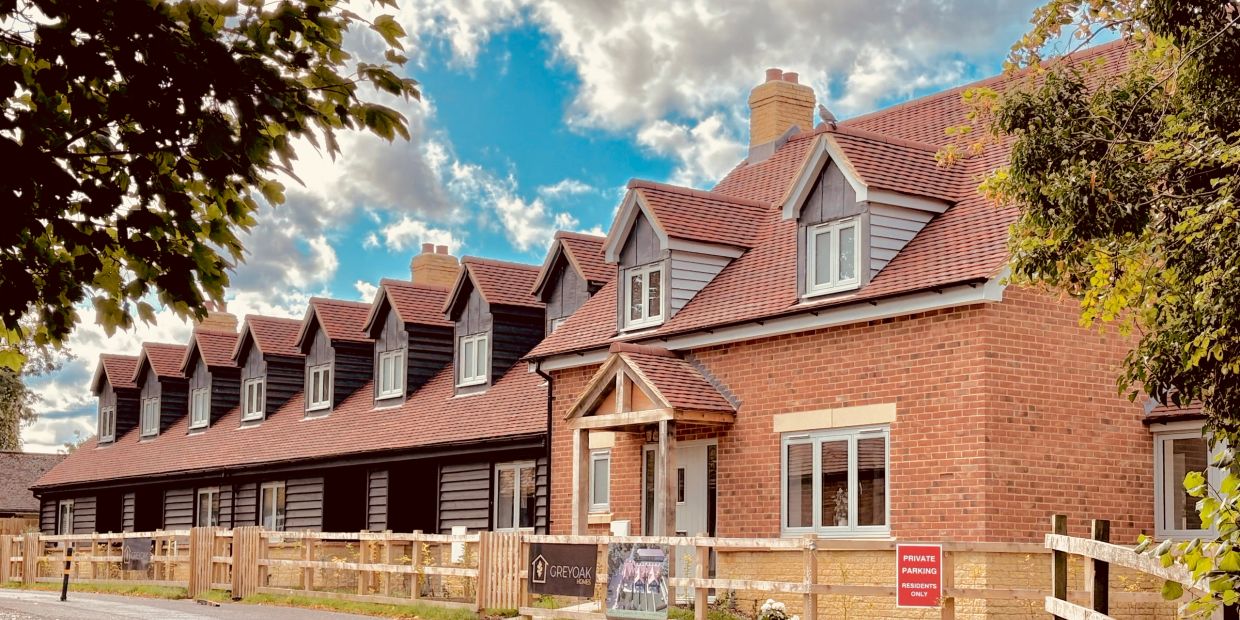 Row of red brick houses under a partly cloudy sky.