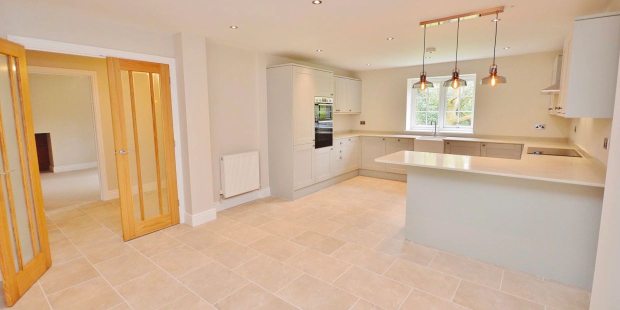 Bright modern kitchen with wooden doors and pendant lights.