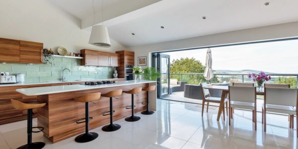 Modern kitchen with wooden cabinets and seating overlooking a balcony.