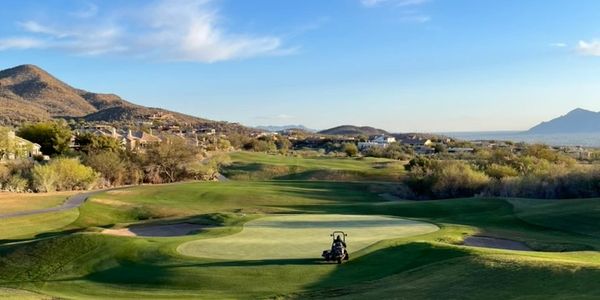 Scenic golf course with clear blue sky and distant mountains.