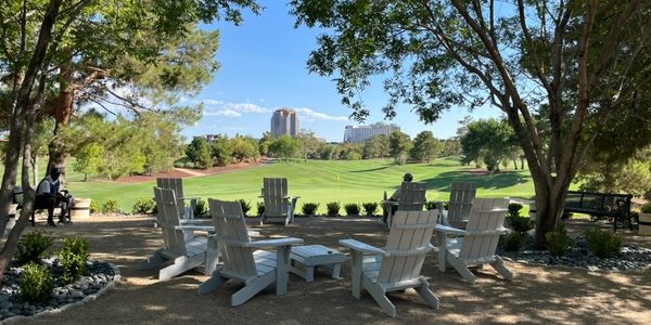White chairs arranged in a circle with a golf course and cityscape in the background.