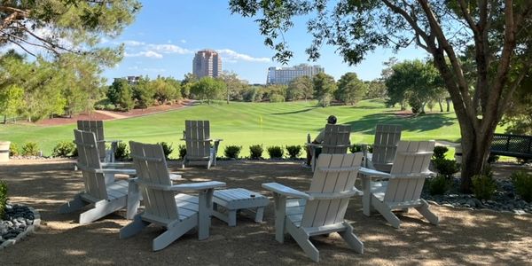White chairs arranged in a circle with a golf course and cityscape in the background.