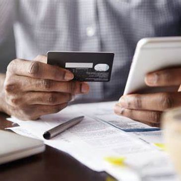 Person holding credit card and phone for online payment.