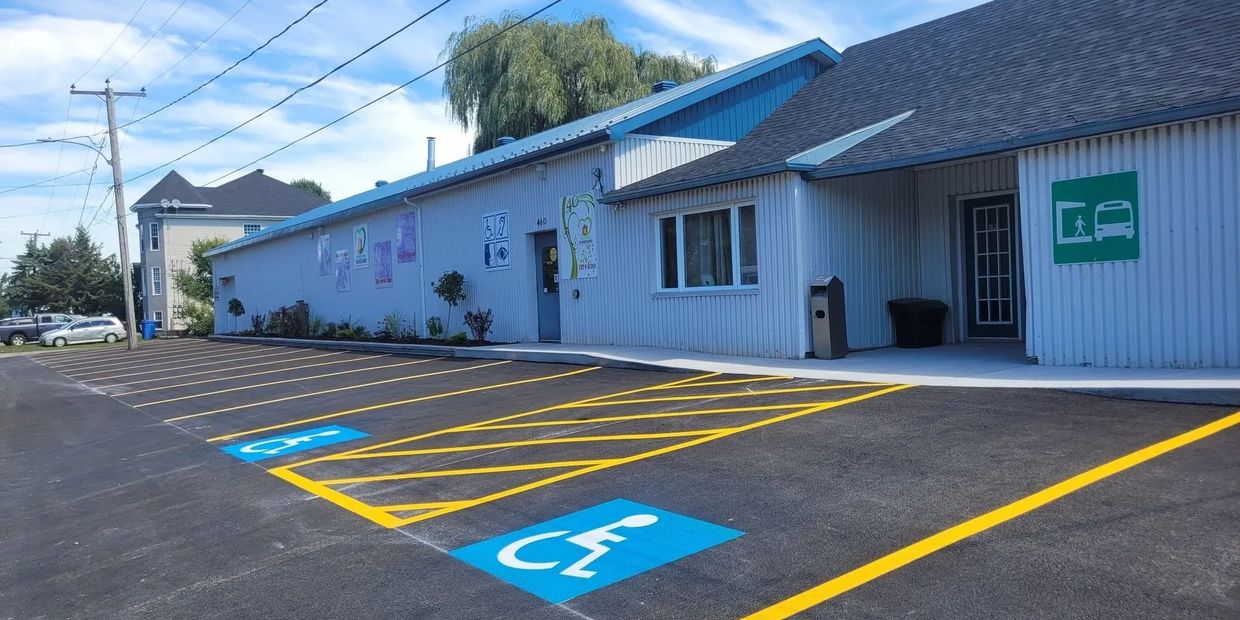 Parking lot with handicap spaces outside a blue-roofed building on a sunny day.