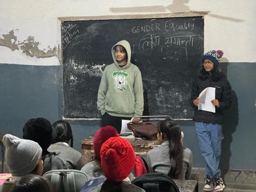 Two girls presenting on gender equality to a classroom of students.