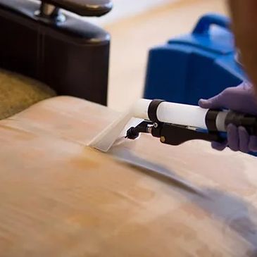 A person cleaning the sofa with a vacuum