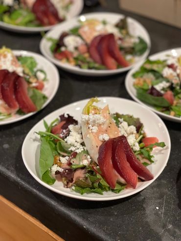 Red wine poached pears, endive, wild baby greens, dragonfruit vinaigrette. The kookery catering.