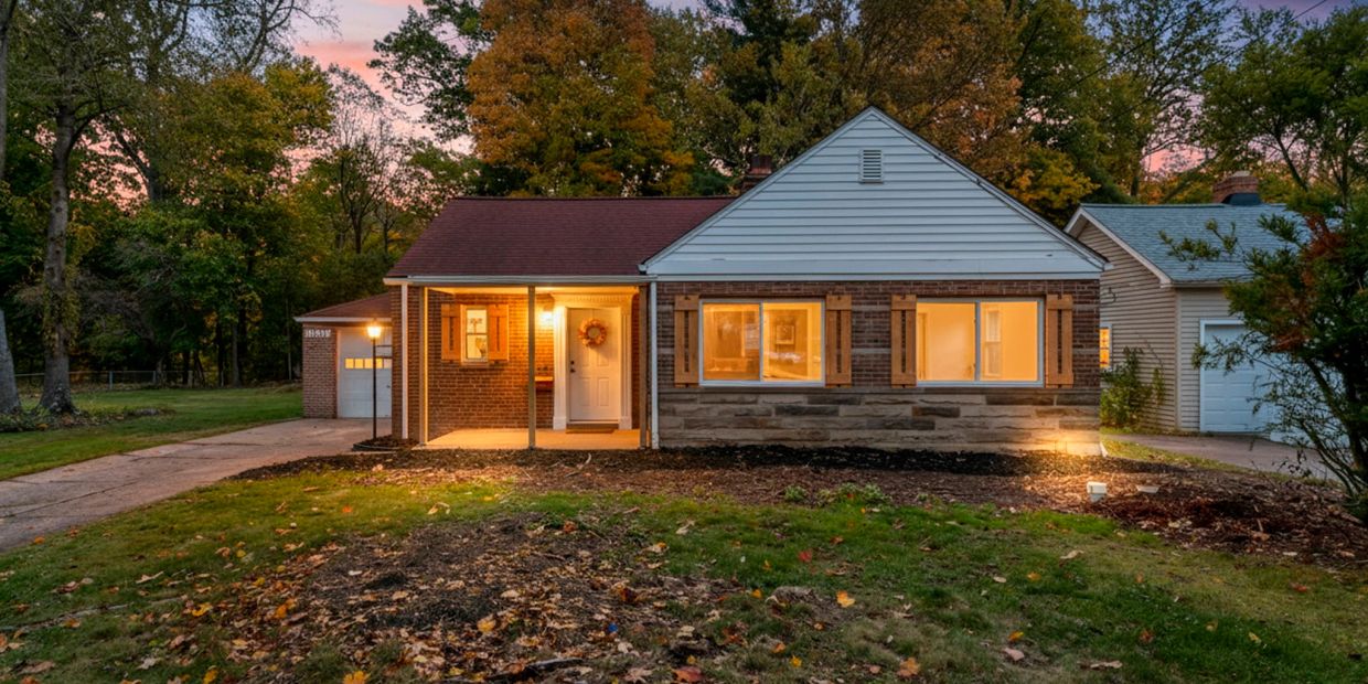 Cozy suburban house at dusk with lights on.