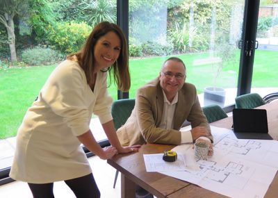 Two professionals reviewing architectural blueprints in a bright meeting room.