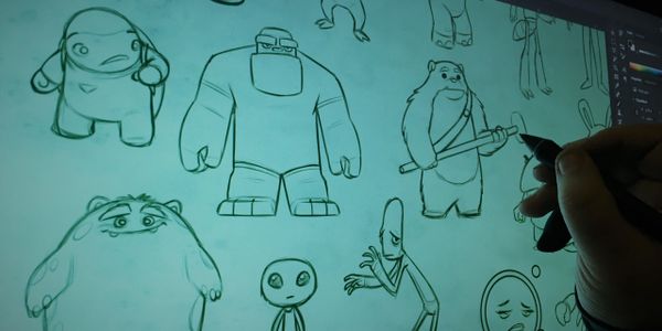 Artist sketching unique cartoon characters on a digital tablet.