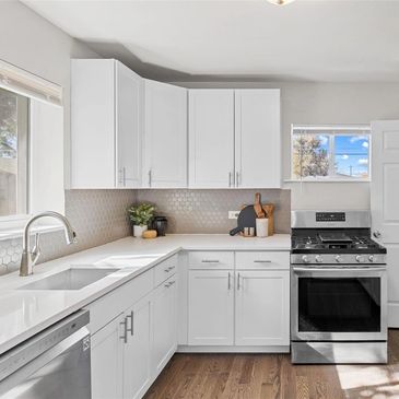 Bright modern kitchen with white cabinets and stainless steel appliances.