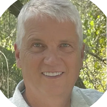 Smiling man with gray hair outdoors.