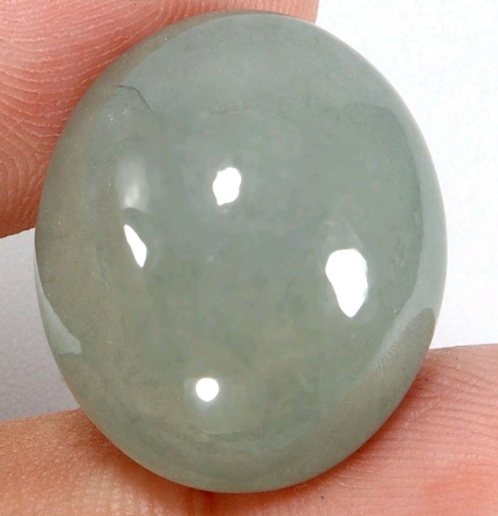 Close-up of a polished, translucent gemstone held between fingers.