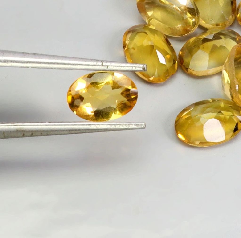 Faceted yellow gemstones with tweezers.