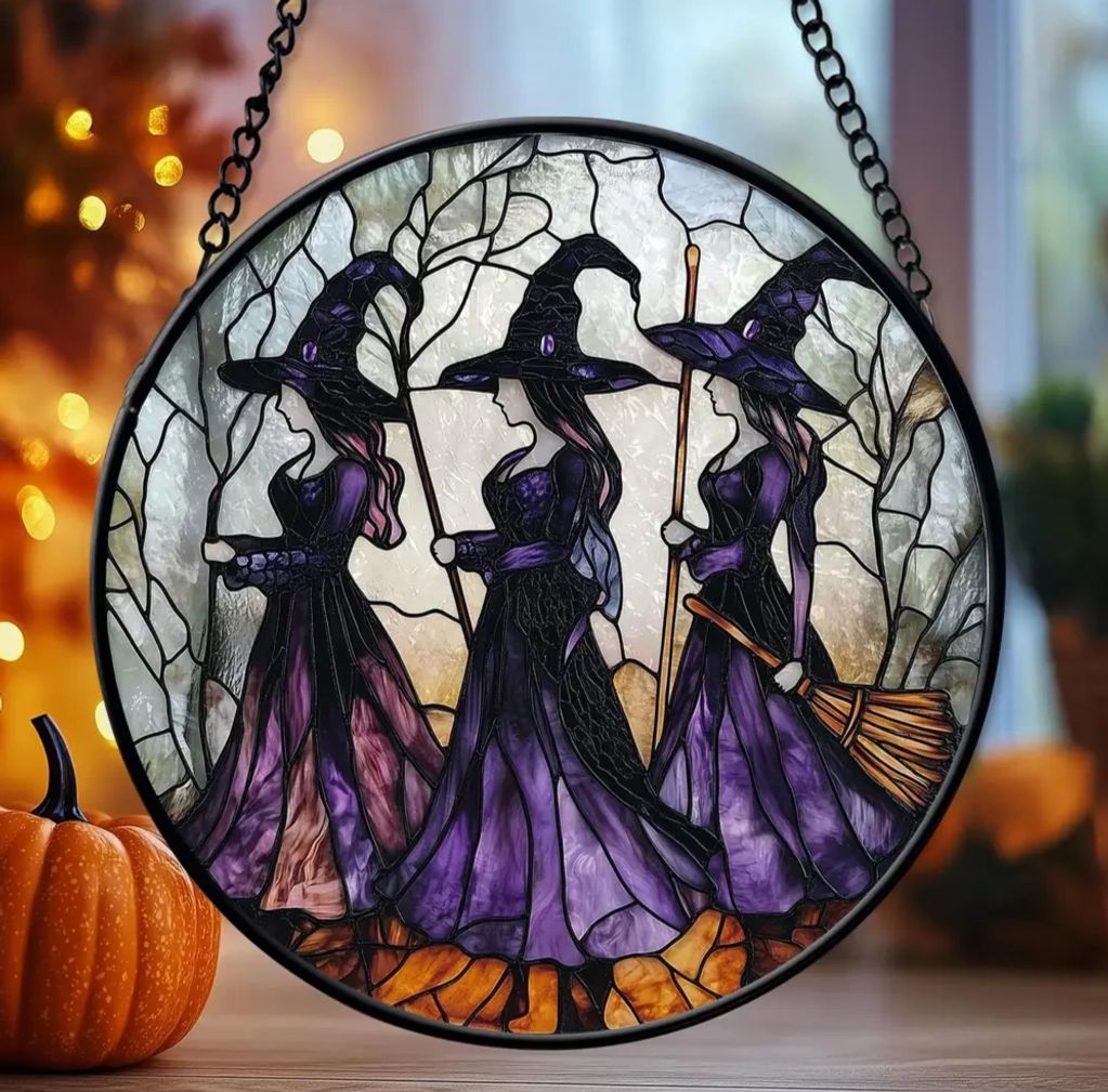 Stained glass art of three witches in purple robes.