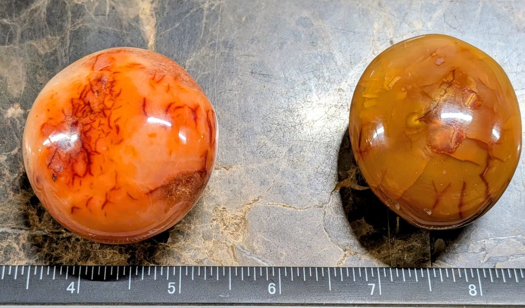 Two polished stone spheres on a marble surface with a ruler.