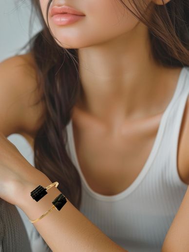 Close-up of a woman wearing a white tank top and a gold bracelet.