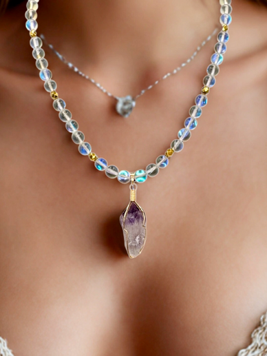 A beaded necklace with a purple crystal pendant.