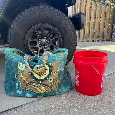 Blue bag and red bucket beside a vehicle tire.