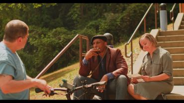 Three people conversing outdoors on steps.
