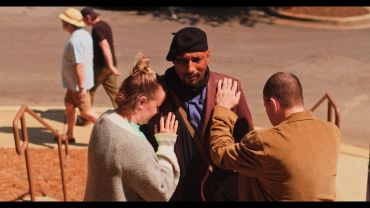 Three people engaging in a moment of connection outdoors.
