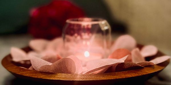 Photograph of a lit candle surrounded by flower petals