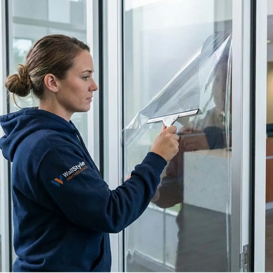 Installing 3M anti-break-in security window film on glass storefront to prevent shatter and theft